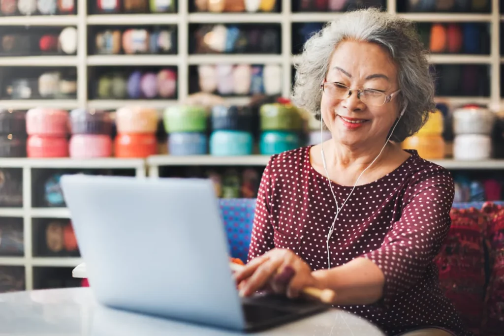 Carla at computer with knitting needles 1200