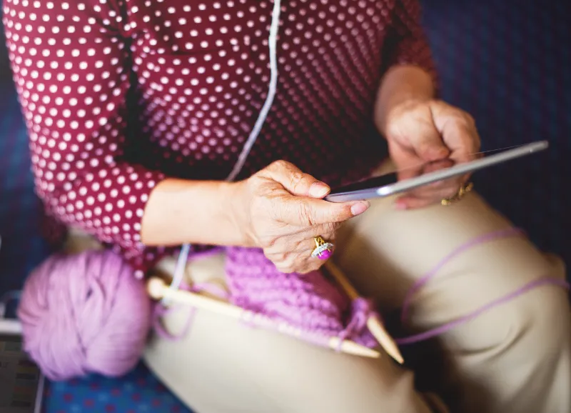 Woman with knitting looking up videos on tablet