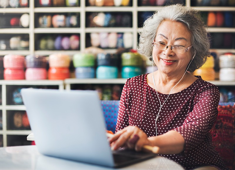 StockImage Carla People Knitters Woman in Yarn Store Looking Up Videos on Computer 800x578px crop 5:5:23